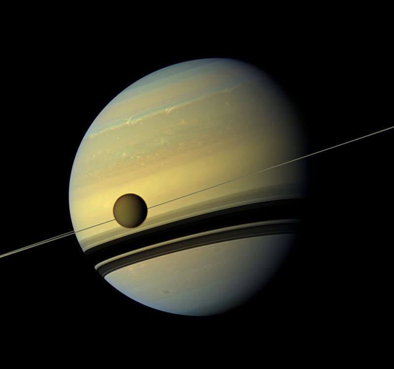 Der große Saturnmond Titan vor den Ringen und dem Planeten
